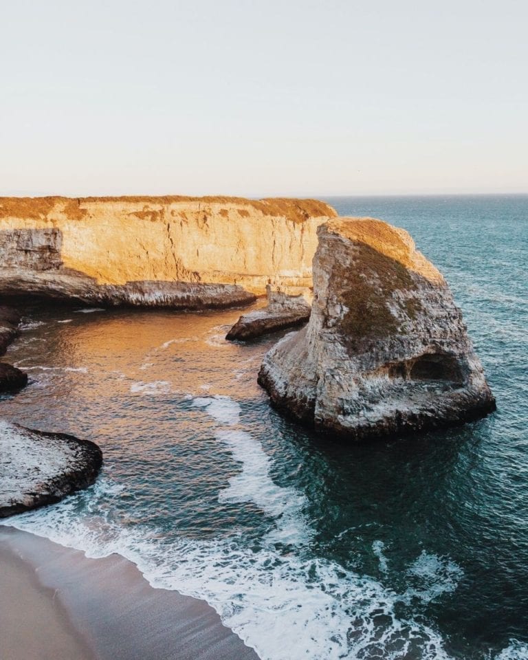 A rock formation shaped like a shark fin sticks out of the Pacific Ocean