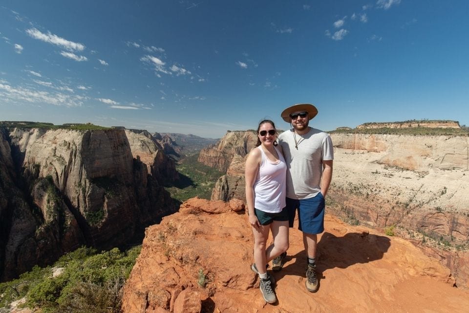 A couple stands atop Observation Point in Zion National Park overlooking Zion Canyon.