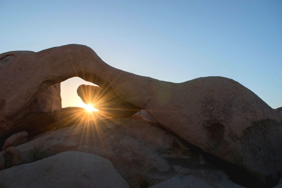 The morning sun peaks through Arch Rock in Joshua Tree National Park