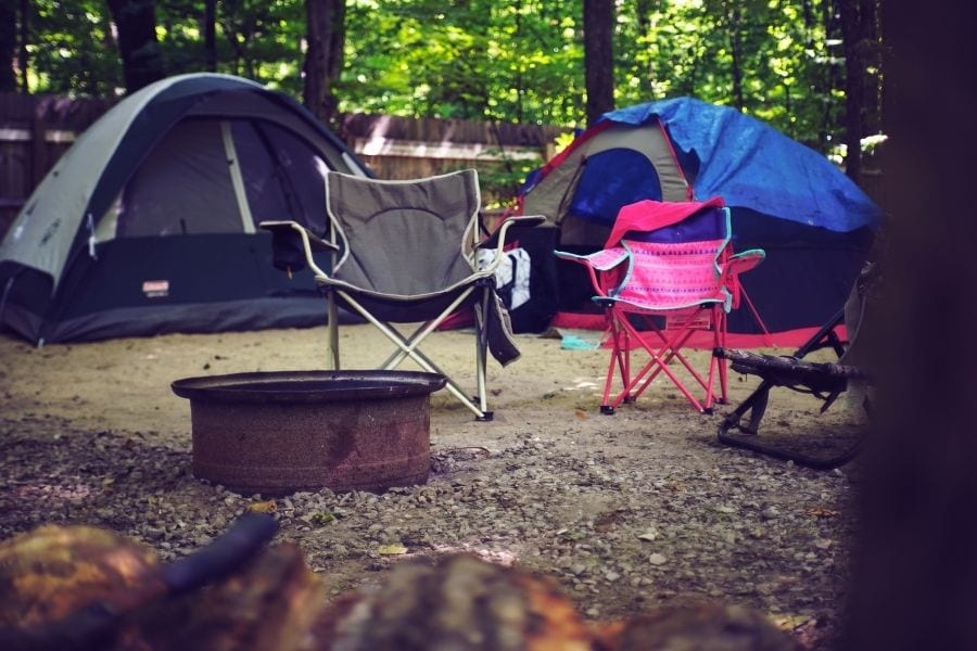 Campchairs and tents set up around a fire pit in a campground