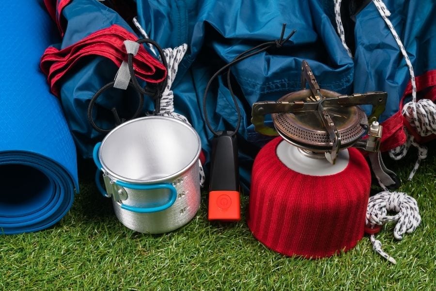 Camping gear is laid on on the grass preparing for a first camping trip.