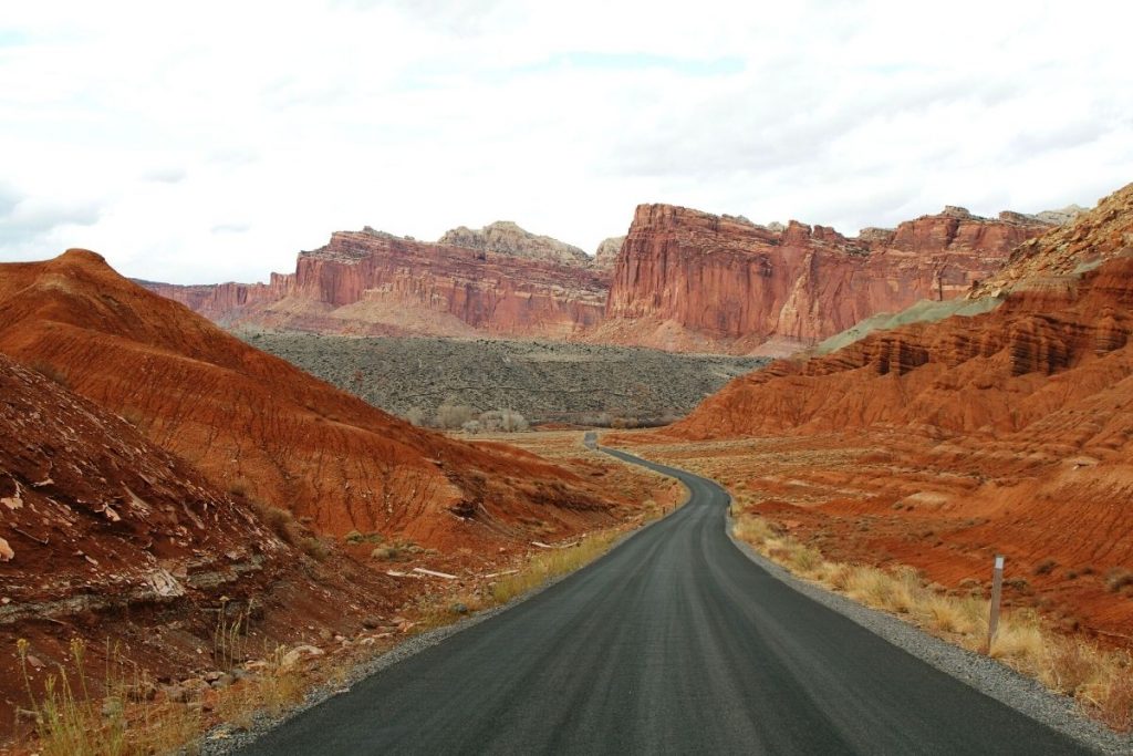 Long black highway winds between red rock mountains in Capitol Reef