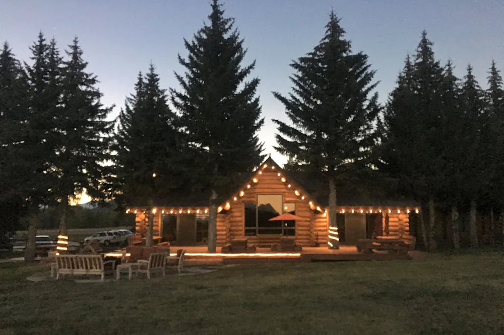 Cabin with lights in a forest at the Hatchet Resort near Grand Teton