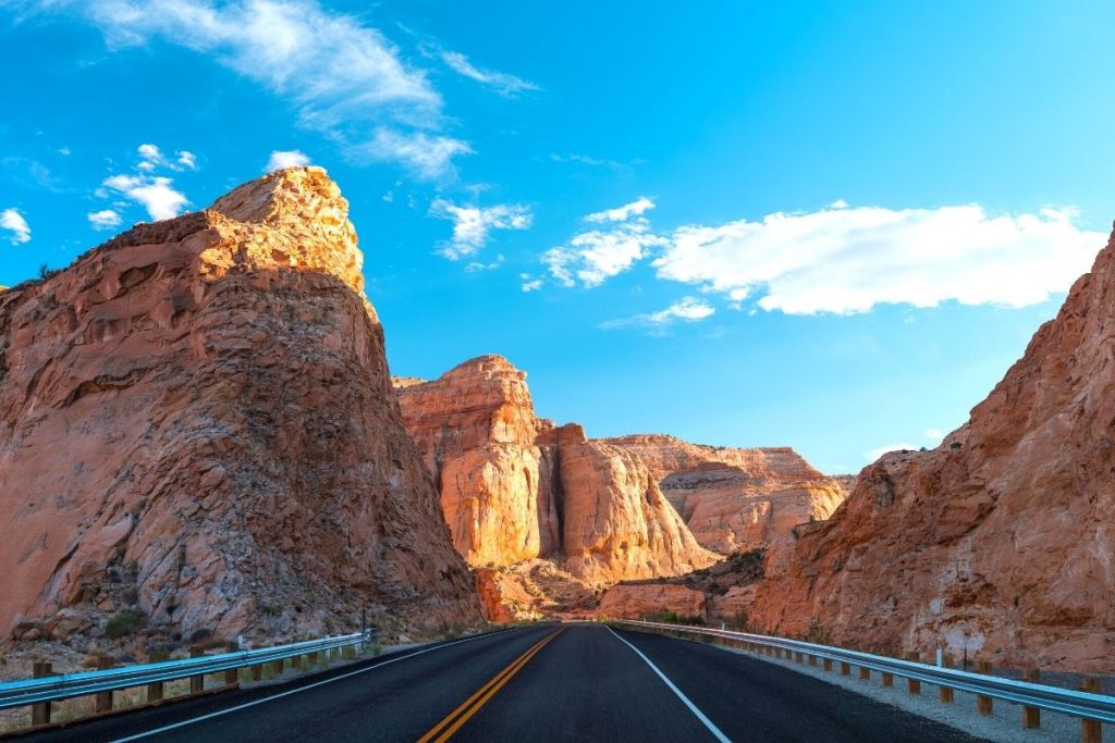 Two lane highway winds between tall red rock mountains along Highway 24 just outside Capitol Reef