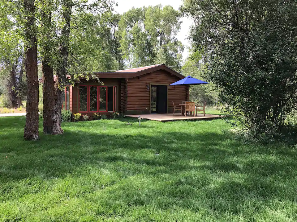 Green grassy lawn and historic log cabin near Grand Teton