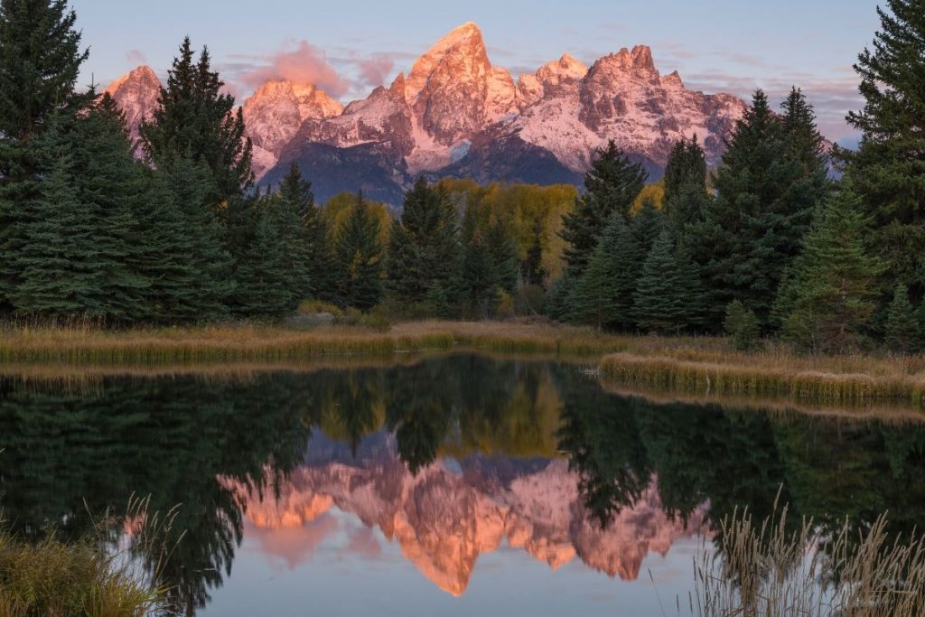 Tetons glow at sunrise reflected in the Snake River at Schwabacher Landing