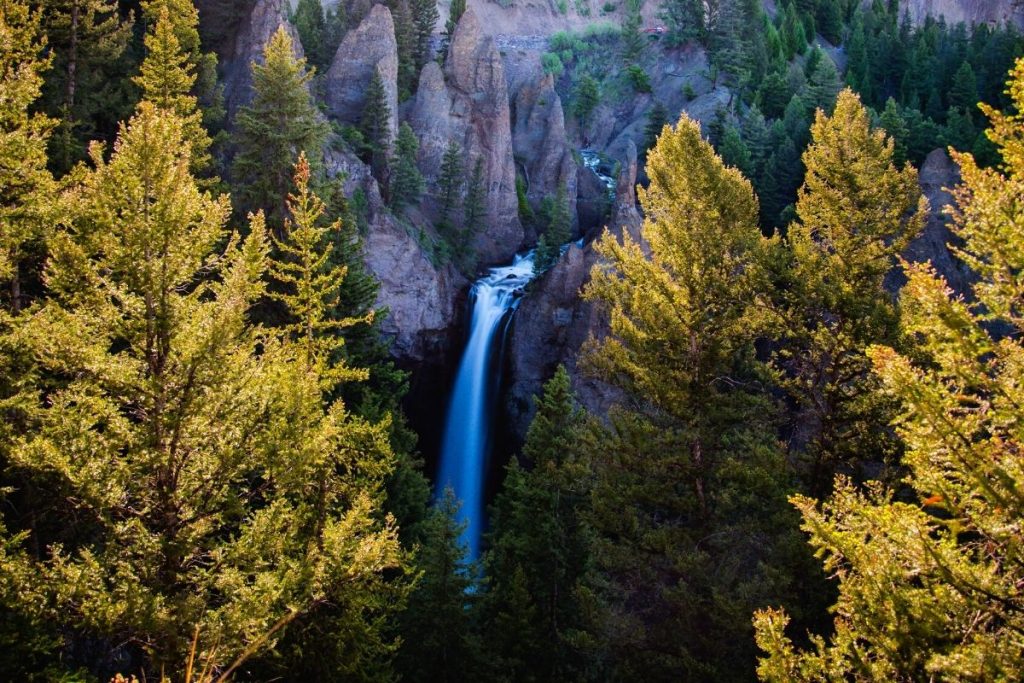 Waterfall framed by trees and rock spires at Tower Fall