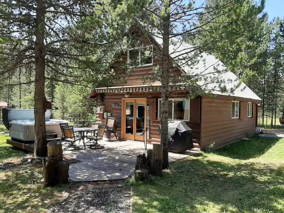 Cabin nestled in a grassy lawn and wooded area