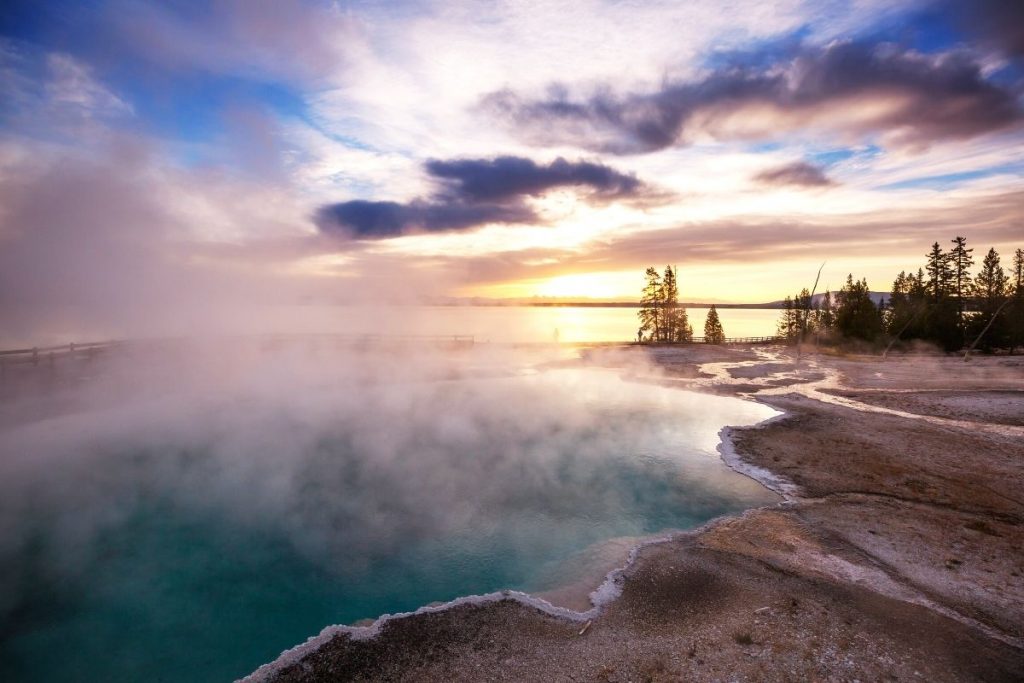 Sunrise over blue hot springs and Yellowstone Lake in West Thumb Geyser Basin